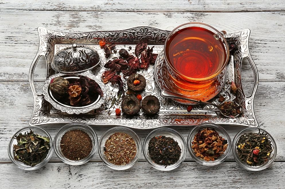 Various kinds of loose leaf tea and a perfect cup of tea on a tray.
