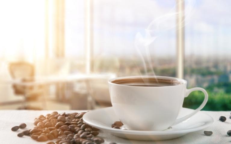 A cup of coffee near a window.