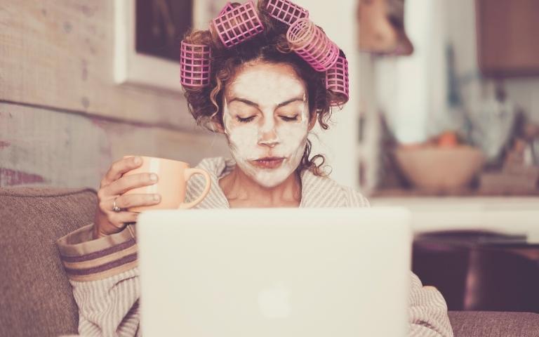 Woman drinking tea with a facemask on.
