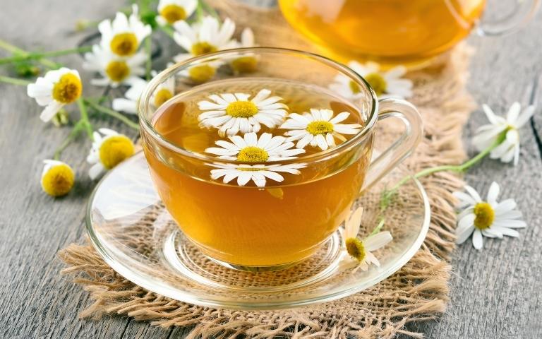 Chamomile infusion with blossoms floating on the tea surface.