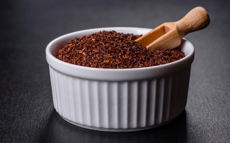 White bowl containing dried leaves of rooibos tea.